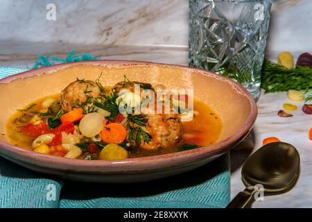 Soupe italienne de mariage avec boulettes de viande, pâtes aux carottes multicolores, petits pois chiches et épinards Banque D'Images