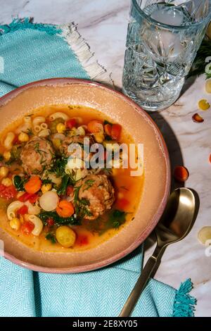 Soupe italienne de mariage avec boulettes de viande, pâtes aux carottes multicolores, petits pois chiches et épinards Banque D'Images