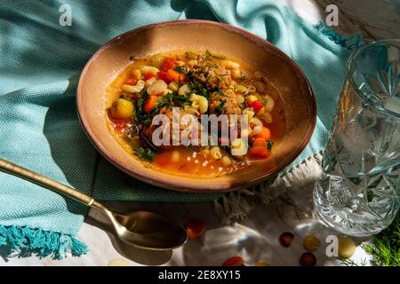 Soupe italienne de mariage avec boulettes de viande, pâtes aux carottes multicolores, petits pois chiches et épinards Banque D'Images