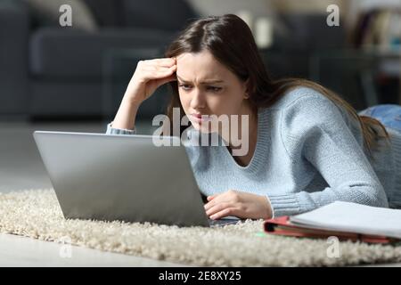 Apprentissage en ligne des élèves confus à l'aide d'un ordinateur portable posé sur le sol à accueil Banque D'Images