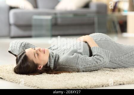 Femme enceinte se relaxant couché sur le sol dans la vie chambre à la maison Banque D'Images