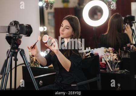 Profession maquilleuse artiste femme passant en revue des produits de beauté sur un blog vidéo au studio de beauté. Femme utilise une lampe annulaire Banque D'Images