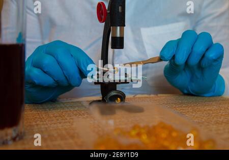 Microscope et mains en laboratoire bleu porter des gants 2021 Banque D'Images