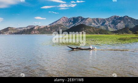 Un homme pêcheur sur un bateau à moteur sur un grand lac sur fond de montagnes - un magnifique à couper le souffle paysage Banque D'Images