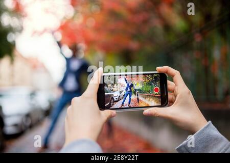 Jeune couple avec smartphone pour la vidéo des médias sociaux en plein air dans la rue. Banque D'Images