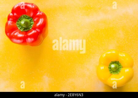 Deux poivrons rouges et jaunes sur le fond jaune, légumes colorés, isolent sur la vue blanche, en grand angle Banque D'Images