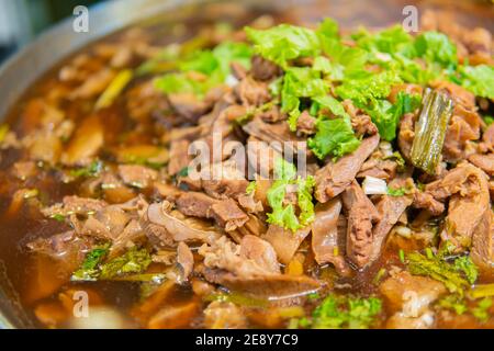 Gros plan de porc cuit dans la sauce avec feuilles de coriandre verte sur le dessus et soupe. Cuisine thaïlandaise. Banque D'Images