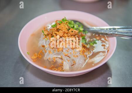 Soupe de nouilles de riz vietnamiennes avec côtes de porc de rechange tenant dans la fourchette et saucisse de style vietnamien, oignon rouge et persil frits sur fond de table en bois Banque D'Images