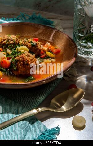 Soupe italienne de mariage avec boulettes de viande, pâtes aux carottes multicolores, petits pois chiches et épinards Banque D'Images