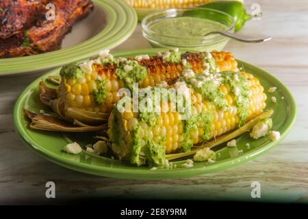 Maïs de rue elote péruvien recouvert de queso fresco fromage et sauce verte épicée aji verde Banque D'Images