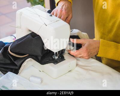 Mains de femmes utilisant la machine électrique à coudre à la maison Banque D'Images