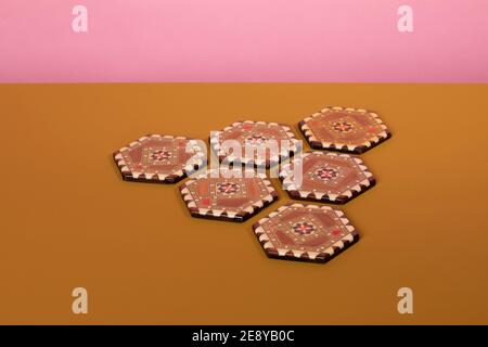 Sous-verres inlamés de marqueterie vintage aux couleurs marron et beige. Un motif oriental éclectique fait de bois de mosaïque sur une table ocre et un dos rose Banque D'Images