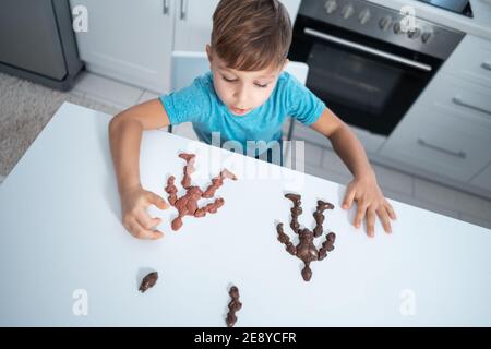 les enfants jouent avec des bonbons au chocolat ou des bonbons sur la table à la cuisine moderne Banque D'Images