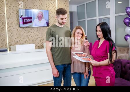 Un médecin de famille spécialisé montre une photo d'une image échographique d'un enfant. Une famille fréquentant une clinique privée de gynécologue. Banque D'Images