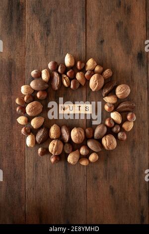 Amandes Shelles, noix, noix de macadamia, pacanes, noisettes disposées en cercle sur fond de bois Banque D'Images