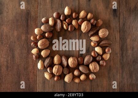 Amandes Shelles, noix, noix de macadamia, pacanes, noisettes disposées en cercle sur fond de bois Banque D'Images