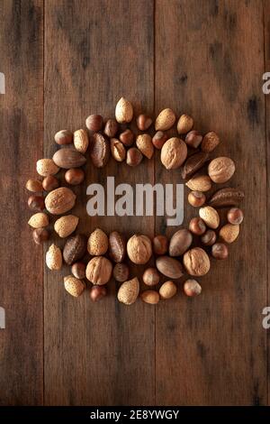 Amandes Shelles, noix, noix de macadamia, pacanes, noisettes disposées en cercle sur fond de bois Banque D'Images