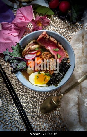 Ramen de thon ahi rose saisi garni d'œufs durs doux bandes d'algues radis et carottes en tranches multicolores Banque D'Images