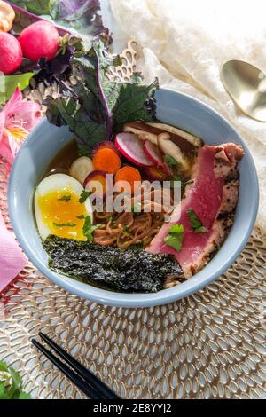 Ramen de thon ahi rose saisi garni d'œufs durs doux bandes d'algues radis et carottes en tranches multicolores Banque D'Images