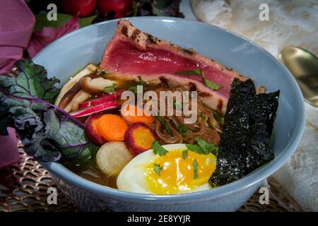 Ramen de thon ahi rose saisi garni d'œufs durs doux bandes d'algues radis et carottes en tranches multicolores Banque D'Images