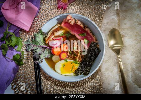 Ramen de thon ahi rose saisi garni d'œufs durs doux bandes d'algues radis et carottes en tranches multicolores Banque D'Images