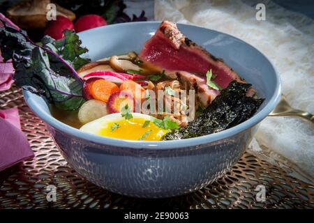 Ramen de thon ahi rose saisi garni d'œufs durs doux bandes d'algues radis et carottes en tranches multicolores Banque D'Images