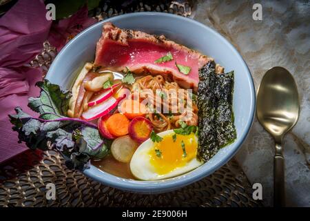 Ramen de thon ahi rose saisi garni d'œufs durs doux bandes d'algues radis et carottes en tranches multicolores Banque D'Images