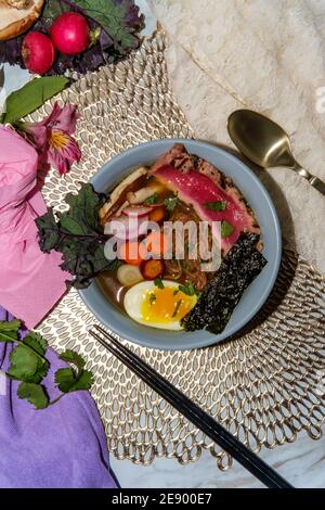 Ramen de thon ahi rose saisi garni d'œufs durs doux bandes d'algues radis et carottes en tranches multicolores Banque D'Images