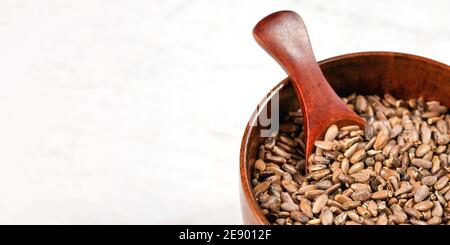 Graines de chardon béni - Silybum marianum - dans une petite tasse en bois sur pierre blanche comme panneau, vue d'en haut, espace pour le côté gauche droit Banque D'Images