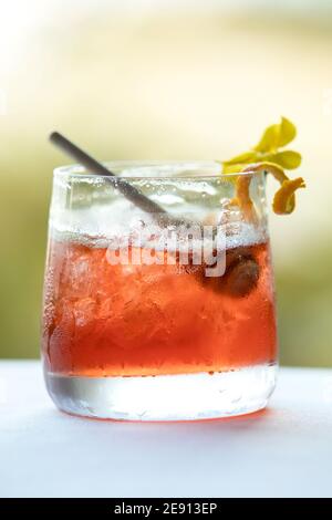 Cocktail rouge coloré inspiré de l'automne, agrumes jaunes et garniture de fleurs Banque D'Images