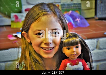 Souriant fille de 8 ans de race blanche avec sa nouvelle poupée sourire à l'appareil photo avec tout le visage Banque D'Images