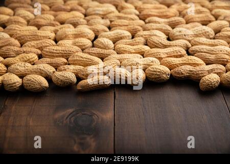 Arachides non pelées sur fond de table en bois avec espace de copie. (arachis hypogaea) graines comestibles. Concept de nutrition saine d'en-cas Banque D'Images