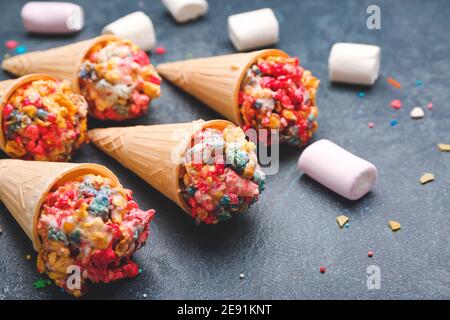 Cornets à motif gaufré avec boules de pop-corn et guimauves sur fond sombre Banque D'Images