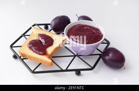 Composition avec une délicieuse confiture de prunes maison sur fond blanc Banque D'Images