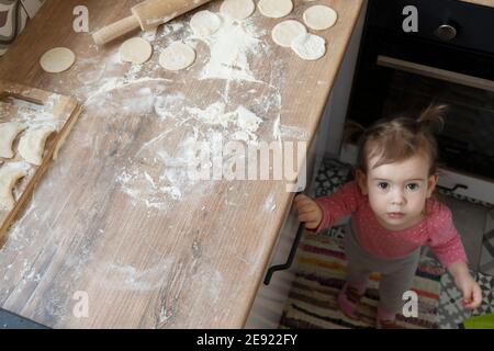 Vue du dessus de la petite fille caucasienne mignonne debout près de la table de cuisson Banque D'Images