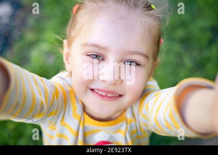 Adorable petite fille prenant selfie avec téléphone mobile à l'extérieur parc vert Banque D'Images