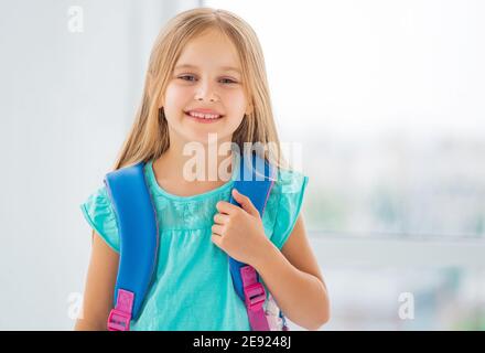 Fille d'école souriante en t-shirt bleu avec sac à dos. Banque D'Images