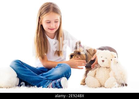 Petite fille attrapant un petit chien dans une pièce lumineuse isolée sur blanc Banque D'Images