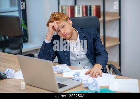 Redhaired un jeune homme contrarié près d'un ordinateur portable Banque D'Images