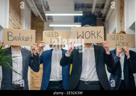 Hommes avec des affiches exigeant le travail debout à l'intérieur Banque D'Images