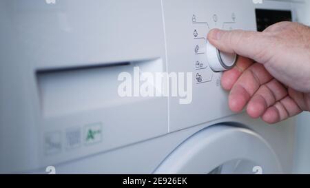 Gros plan main de l'homme à l'aide d'un lave-linge Banque D'Images