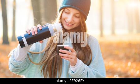 Jolie fille avec des thermos dans le parc d'automne Banque D'Images