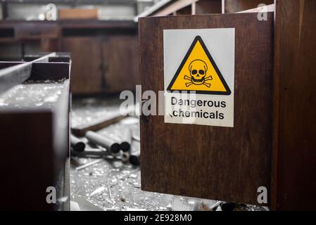 Triangle jaune avec crâne noir et crossos signe de produits chimiques dangereux sur la porte ouverte de placard en bois dans le laboratoire abandonné après cambriolage équipement Banque D'Images