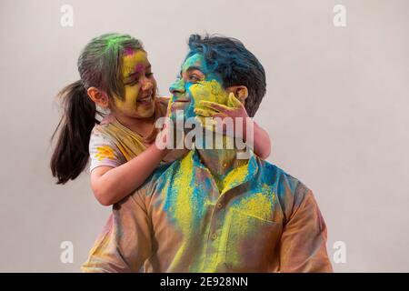 Père souriant à sa petite fille mettant le gulal sur lui face Banque D'Images