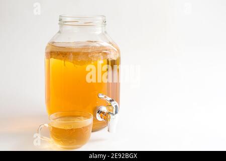 Kombucha-une boisson à base de champignons du thé dans un pot en verre avec robinet. Tasse transparente avec une boisson à base de levure à base de champignons japonais-méduse. Blanc b Banque D'Images