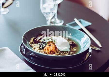 Soupe de ramen de bœuf avec œufs pochés et légumes à un restaurant Banque D'Images