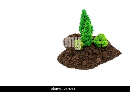 Petite zone forestière en forme de coeur faite de terre et de jouet arbres isolés sur blanc Banque D'Images