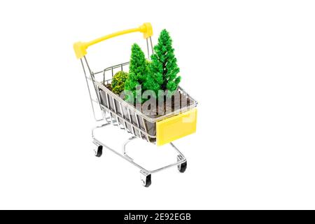 Gros plan d'un petit chariot de shopping avec des arbres de terre et de jouets isolés sur blanc. Concept créatif de soin des forêts. Banque D'Images
