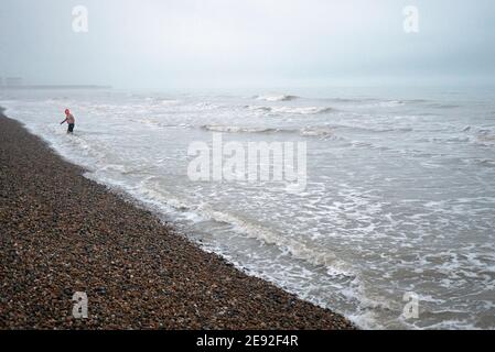 Brighton Beach dans un après-midi froid de janvier avec UNE chambre simple Nageur sortant de l'eau au loin Banque D'Images