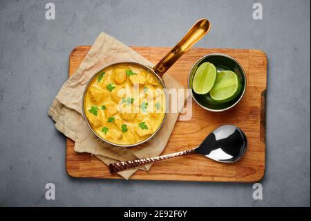Poulet Korma dans un récipient en cuivre sur une table en béton gris. Cuisine indienne plat de cari à la viande avec masala au lait de coco. Cuisine asiatique Banque D'Images